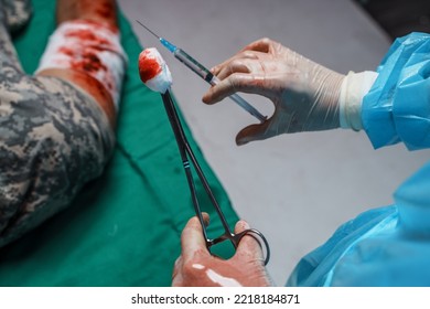 Shot Of Operating Room There Are Injured Soldier And Surgeon Holding Scissors And Syringe.