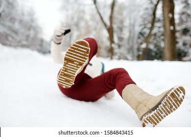 Shot Of Person During Falling In Snowy Winter Park. Woman Slip On The Icy Path, Fell And Lies. Danger Of Season Trauma.