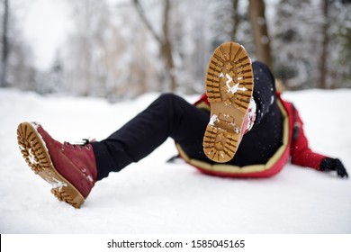 Shot Of Person During Falling In Snowy Winter Park. Woman Slip On The Icy Path, Fell And Lies. Danger Of Season Trauma.