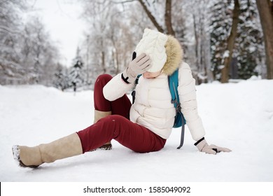 Shot Of Person During Falling In Snowy Winter Park. Woman Slip On The Icy Path, Fell And Lies. Danger Of Season Trauma.