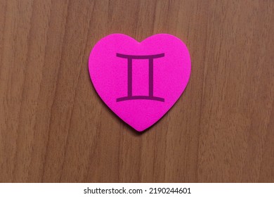 Shot of a pink paper heart, in which a zodiac sign is drawn above, specifically the sign is Gemini - Powered by Shutterstock