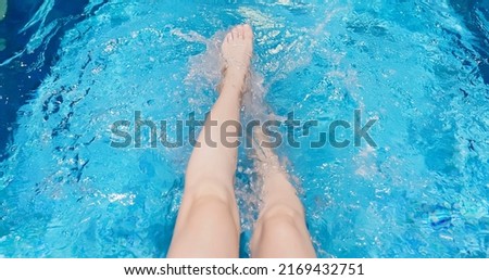 shot from point of view - carefree young woman kicks feet underwater in the pool while summer vacation