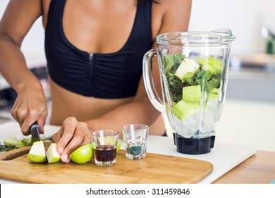 Shot of the preparation of a green detox juice. Hands of a woman cutting apple. - Powered by Shutterstock