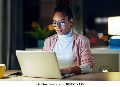 Aufnahme einer ziemlich glücklichen jungen Unternehmerin, die mit Laptop arbeitet und im Büro sitzt.