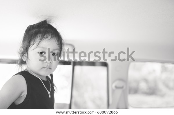 Shot of a\
pretty little asian girl have sad face to the camera sitting on a\
backseat of a car.black and white\
tone.