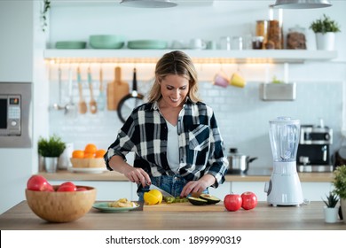 Shot Of Pretty Mature Woman Cutting Fruit While Preparing Detox Drink In The Kitchen At Home.