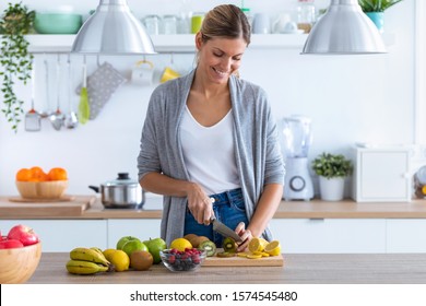 Shot of pretty young woman cutting kiwi for preparing detox beverage in the kitchen at home. - Powered by Shutterstock