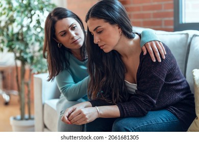 Shot of pretty young woman supporting and comforting her sad friend while sitting on the sofa at home. - Shutterstock ID 2061681305