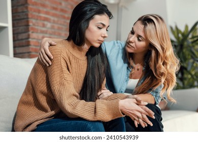 Shot of pretty young woman supporting and comforting her sad friend while sitting on the sofa at home. - Powered by Shutterstock