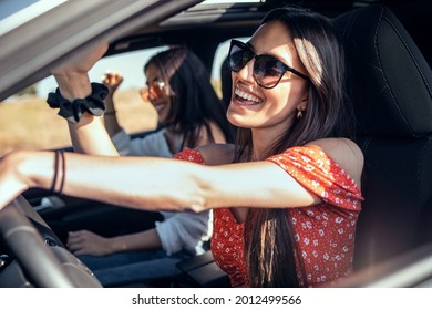 Shot of pretty young women singing while driving a car on road trip on beautiful summer day. - Powered by Shutterstock