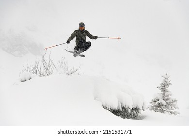Shot of professional freeride skier masterfully jumping in the air over a snow-covered mountain slope. Freeride skiing concept