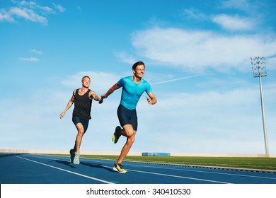 Shot of professional male athletes passing over the baton while running on the track. Athletes practicing relay race on racetrack.