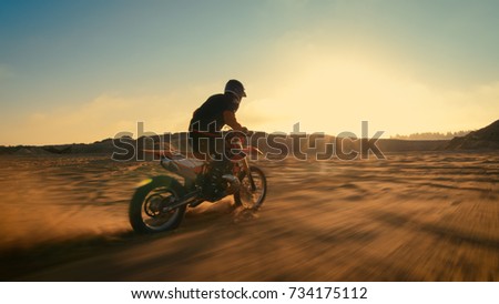 Shot of the Professional Motocross Driver Riding on His FMX Motorcycle on the Extreme Off-Road Terrain Track. Blur motion.