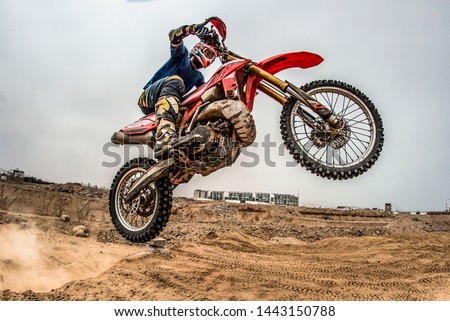 Shot of the professional motocross rider on his motorcycle on the extreme terrain track. Biker flying on a motocross motorcycle. Construction background and sky.