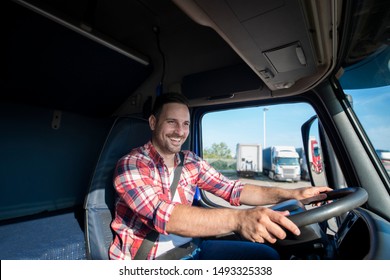 Shot of professional truck driver in casual clothing wearing seat belt on and driving his truck to destination. Smiling trucker enjoying his job. Transportation services.