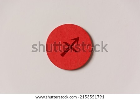 shot of a red wooden circle on a white background with a zodiac sign engraved on it, specifically the Sagitarius sign