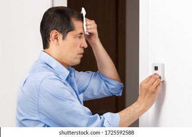 Shot Of A Sad Business Man Sweating Suffering A Heat Stroke And Adjusting A Digital Thermostat In The Office
