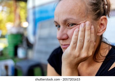 Shot Of Sad Woman Sitting Outdoor. Woman Outdoors In Nature Holding Her Head Expressing Pain, Exhaustion, Sadness Or Depression. Concerned Serious Mature Woman. Photo Of A Beautiful Thoughtful Female.