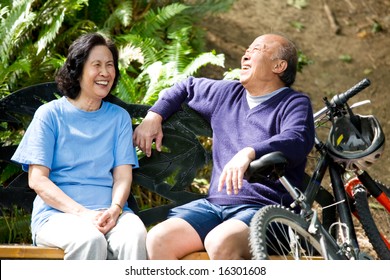 A Shot Of Senior Asian Couple Sitting On A Bench At A Park