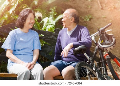 A Shot Of Senior Asian Couple Sitting On A Bench At A Park