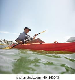 Shot Of Senior Man Kayaking On Lake On A Summer Day. Mature Man Paddling A Kayak In Lake.