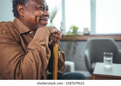 Shot of a senior man looking thoughtfully out of a window at home. Positive African American senior grandfather with grey hair and beard sitting at home. Elderly man sitting alone at home - Powered by Shutterstock