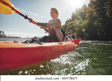 Shot Of Senior Woman Canoeing In Lake On A Summer Day. Mature Woman Paddling A Kayak In Lake.