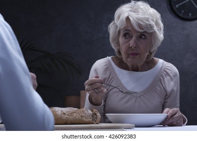 Shot Of A Senior Woman Eating Soup And Looking At Her Husband