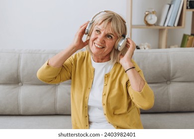 Shot of a senior woman wearing headphones while listening to music at home. Some tunes will stay my favourite forever.  - Powered by Shutterstock