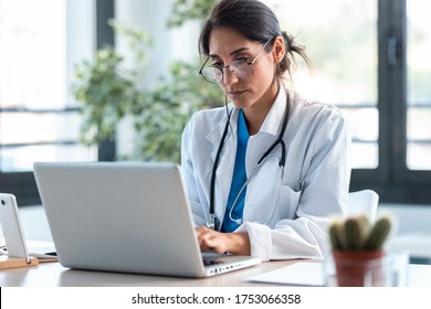 Shot of serious female doctor working with her laptop in the consultation.