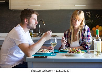 Shot Of Serious And Unhappy Young Couple Eating Quinoa Salad In The Kitchen At Home.