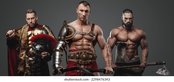 Shot of shirtless gladiator and muscular viking with greek soldier against grey background.