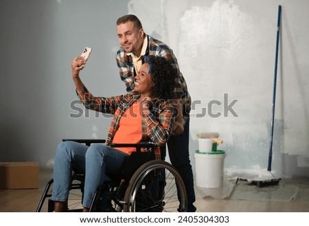 The shot shows a room that is being renovated, it is not yet finished. In the center of the room is a man and a woman in a wheelchair. They are taking selfies, posing for the camera ストックフォト © 