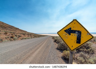 Shot up sign showing a curve to the left in the Alvord Desert in Harney County in Oregon
