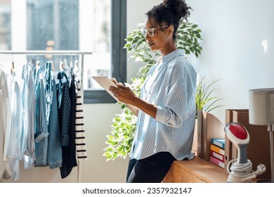 Shot of smart beautiful fashion designer working with digital tablet of new collection of clothes in the sewing workshop. - Powered by Shutterstock