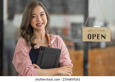 Shot Of Smiling Asian Young Sme Small Business Owner Wearing Apron And Standing White Ipad And Open Sign Coffee Shop Door, Asian Business Woman Barista Cafe Owner SME Entrepreneur Seller Concept