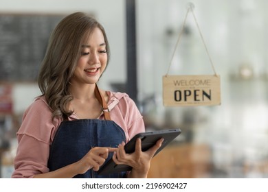 Shot Of Smiling Asian Young Sme Small Business Owner Wearing Apron And Standing White Ipad And Open Sign Coffee Shop Door, Asian Business Woman Barista Cafe Owner SME Entrepreneur Seller Concept