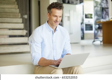 Shot of a smiling casual man using his laptop while relaxing at home.