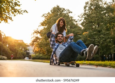 Shot of a smiling happy couple having fun skateboarding outdoors. - Powered by Shutterstock