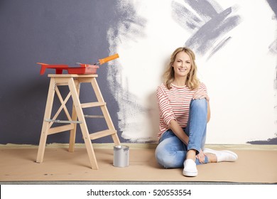 Shot Of A Smiling Middle Aged Woman Painting Wall In Her New Home Under Construction.