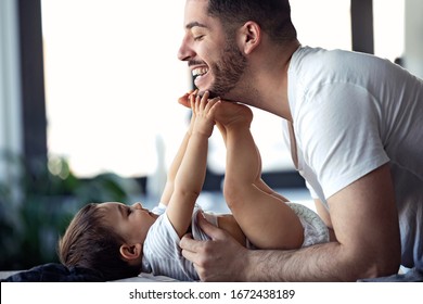 Shot of smiling young father has fun with little baby while changing his nappy at home. - Powered by Shutterstock