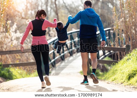 Shot of sporty young couple with her little son playing and enjoying the time together outdoor.