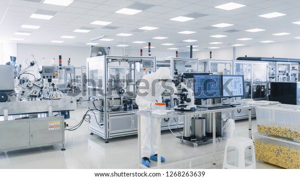 Shot of Sterile\
Pharmaceutical Manufacturing Laboratory where Scientists in\
Protective Coverall\'s Do Research, Quality Control and Work on the\
Discovery of new Medicine.