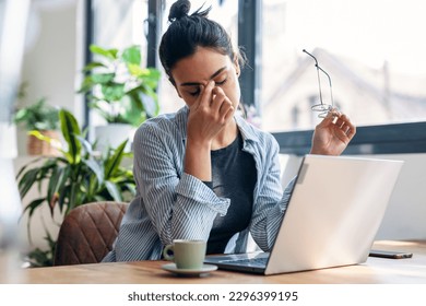 Shot of stressed business woman working from home on laptop looking worried, tired and overwhelmed - Shutterstock ID 2296399195