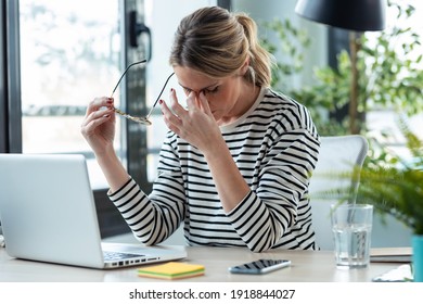 Shot Of Stressed Mature Business Woman Looking Worried, Tired And Overwhelmed While Working With Laptop On A Desk In The Office At Home. 