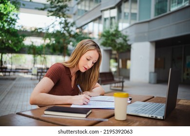 Shot Of Student Young Woman Studying By Taking Notes Of The Book. She Is At The Uni Campus