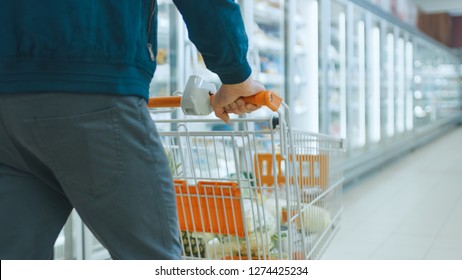 Shot At The Supermarket: Of The Man Pushing Shopping Cart Full Of Products Through Frozen Goods And Dairy Section Of The Store.