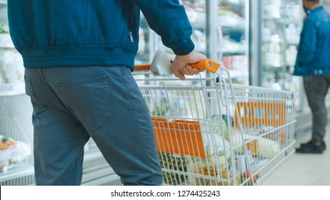 Shot At The Supermarket: Of The Man Pushing Shopping Cart Full Of Products Through Frozen Goods And Dairy Section Of The Store.