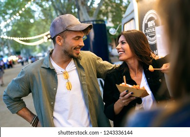 Shot of sweet attractive couple eating potatoes together in eat market in the street. - Powered by Shutterstock