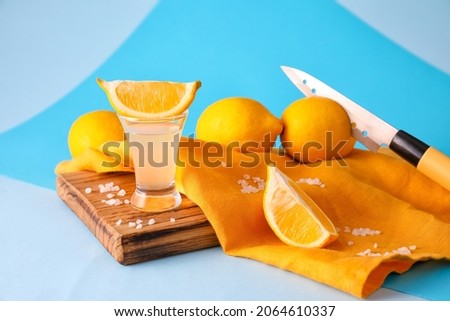 Shot of tasty tequila with lemon on color background